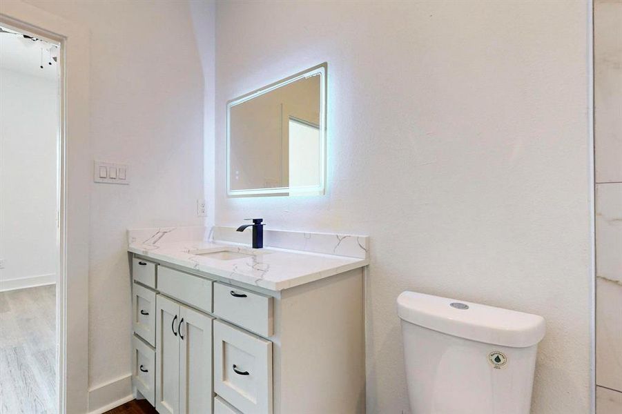 Bathroom featuring wood-type flooring, toilet, and vanity