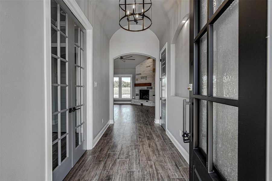 Hall with high vaulted ceiling, french doors, and an inviting chandelier