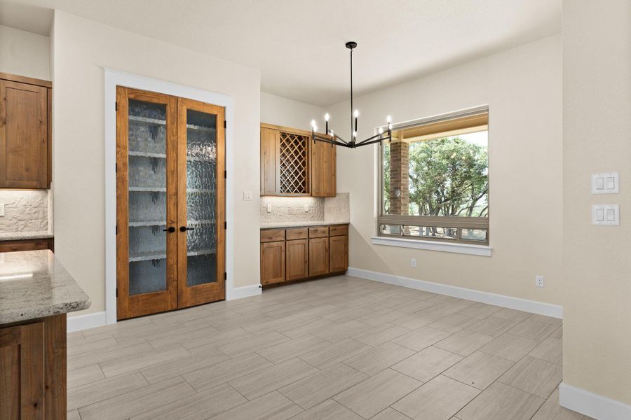Unfurnished dining area featuring a chandelier, wood tiled floors, and french doors Unfurnished dining area featuring a chandelier, wood tiled floors, and french doors