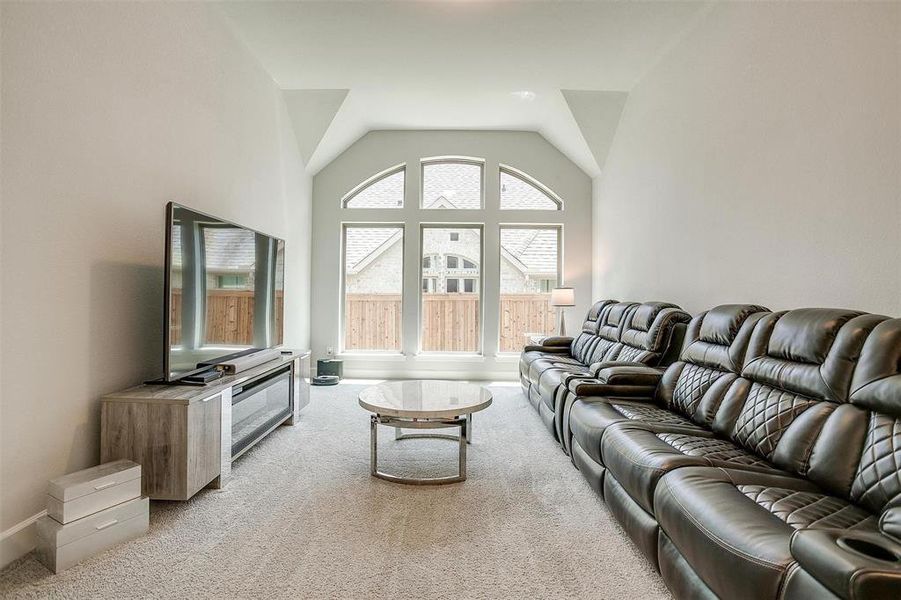 Living room featuring light colored carpet, lofted ceiling, and baseboards Living room featuring light colored carpet, lofted ceiling, and baseboards