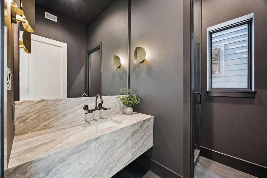 Full bath features a floating sink with designer sconces and a walk-in shower. Full bath features a floating sink with designer sconces and a walk-in shower.