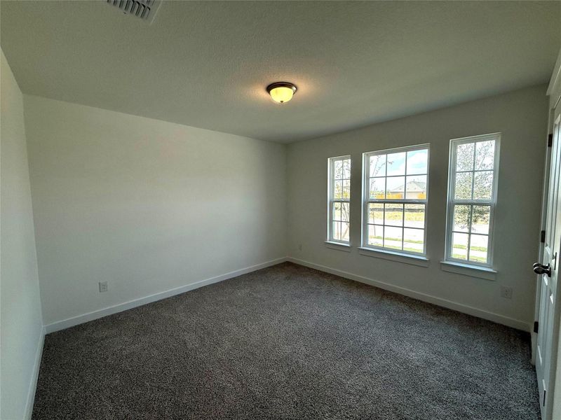 Unfurnished room featuring dark colored carpet and a textured ceiling Unfurnished room featuring dark colored carpet and a textured ceiling