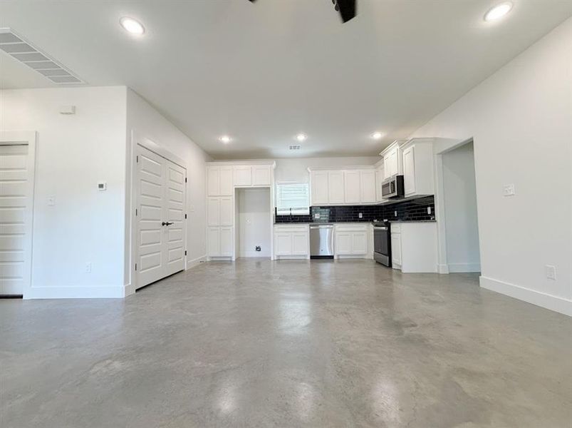 Kitchen with white cabinets, tasteful backsplash, open floor plan, and recessed lighting Kitchen with white cabinets, tasteful backsplash, open floor plan, and recessed lighting