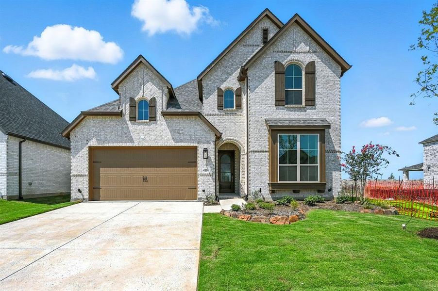 French country style house featuring brick siding, concrete driveway, and a garage French country style house featuring brick siding, concrete driveway, and a garage