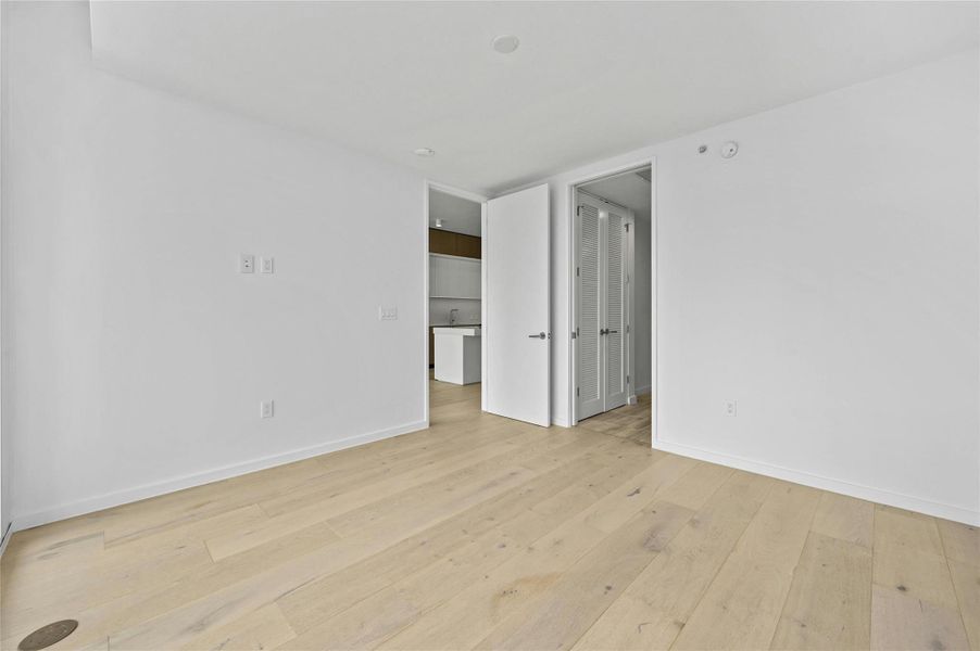 The primary suite offers wide-plank oak floors, clean modern lines, and space for a king-size bed. A walk-in closet provides ample storage with double hanging rods and shelving. The ensuite bath features a soaking tub and shower with floor-to-ceiling tile, recessed niches, and sleek modern fixtures for a spa-like retreat. The primary suite offers wide-plank oak floors, clean modern lines, and space for a king-size bed. A walk-in closet provides ample storage with double hanging rods and shelving. The ensuite bath features a soaking tub and shower with floor-to-ceiling tile, recessed niches, and sleek modern fixtures for a spa-like retreat.