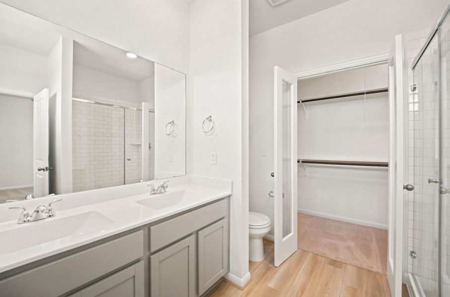 A spacious double vanity and a nearby walk-in closet highlight this modern primary bathroom.