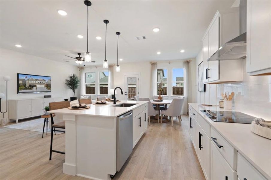 Kitchen featuring a sink, black electric cooktop, wall chimney exhaust hood, dishwasher, and a ceiling fan