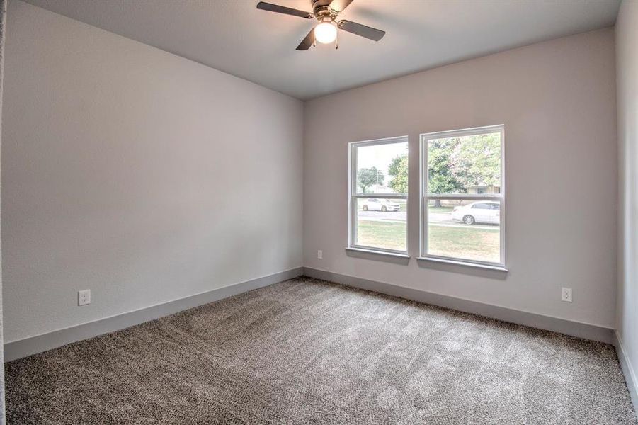 Carpeted empty room with a ceiling fan and baseboards Carpeted empty room with a ceiling fan and baseboards