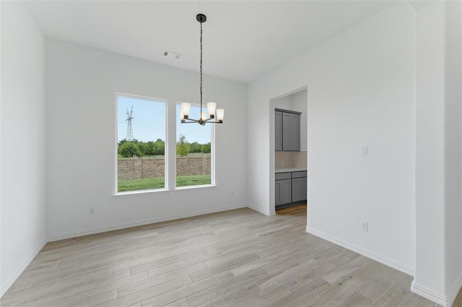 This space features light-colored plank flooring, white walls, and a modern chandelier