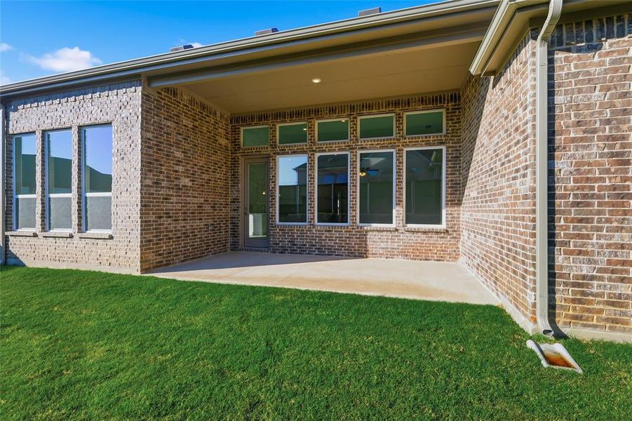 View of exterior entry with a patio, brick siding, and a yard View of exterior entry with a patio, brick siding, and a yard