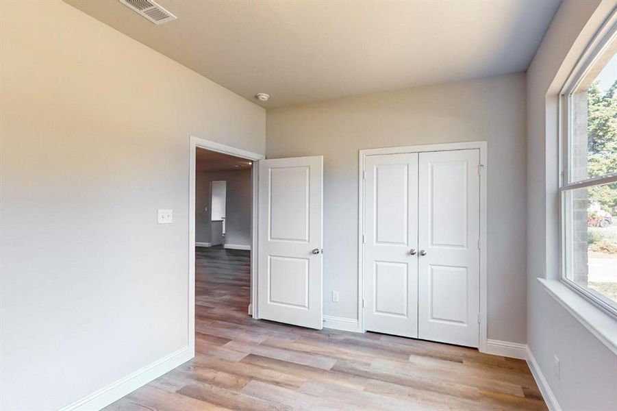 Unfurnished bedroom with a closet, light hardwood / wood-style flooring, and multiple windows