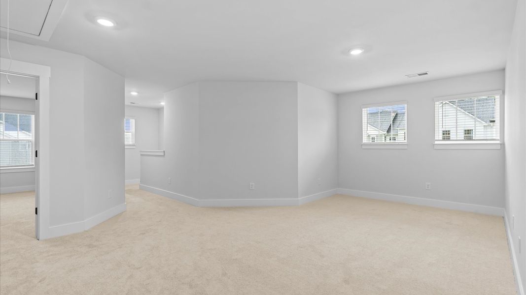 Vibrant loft with carpeted flooring and flexible space for work, play, or relaxing at Silo Ridge by DRB Homes in Anderson, SC