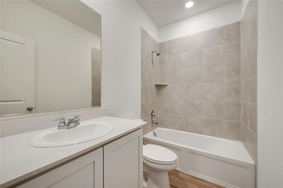 Full bathroom featuring large vanity, hardwood / wood-style floors, toilet, and tiled shower / bath combo