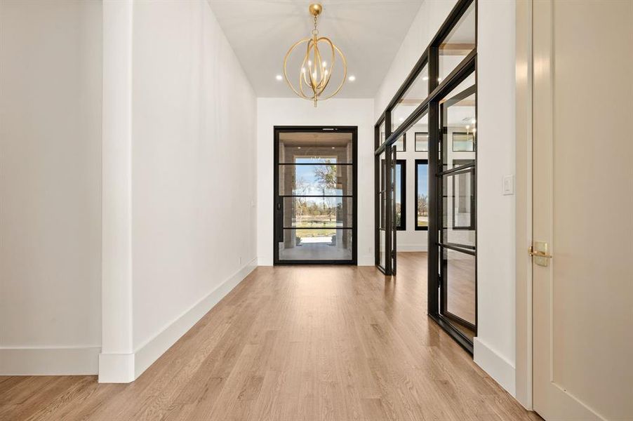 Doorway with wood finished floors and hanging lights