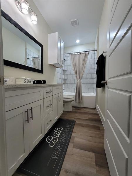 Hallway bathroom with double sinks, custom tile job for bath/ shower and white shaker cabinets self closing with hardware plenty of storage space.