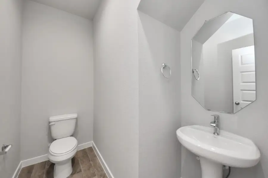 This half bathroom features a stylish pedestal sink, modern hardware, and bright recessed lighting, creating a sleek and inviting space. Sample photo of completed home with similar floor plan. Actual colors and selections may vary.