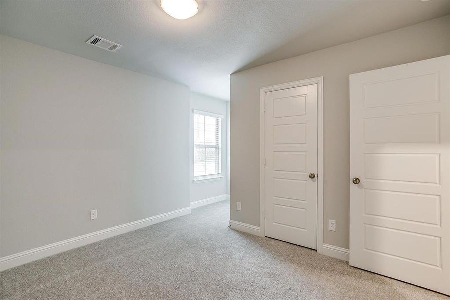 Unfurnished bedroom featuring carpet floors, baseboards, visible vents, and a textured ceiling