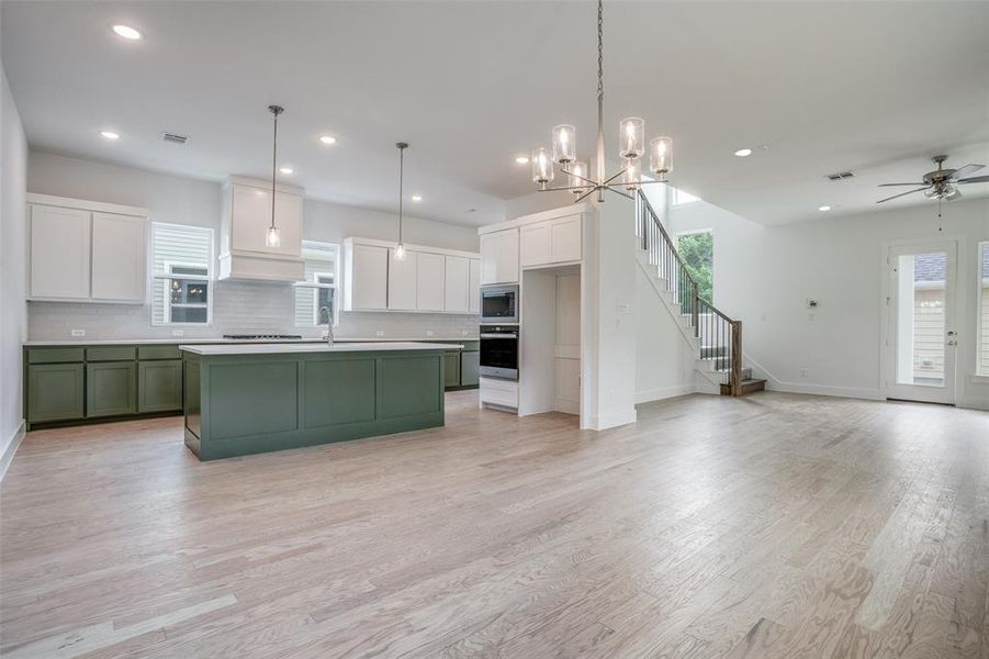 Kitchen with white cabinets, a kitchen island with sink, pendant lighting, and appliances with stainless steel finishes