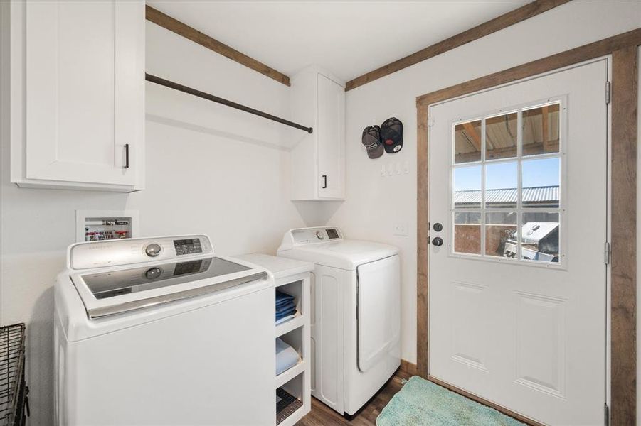 Laundry area featuring cabinet space, washing machine and clothes dryer, and dark wood-type flooring Laundry area featuring cabinet space, washing machine and clothes dryer, and dark wood-type flooring