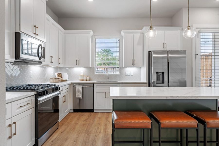 Subtle design accents like brass hardware and pendant lighting add warmth and contrast to the clean cabinetry and neutral palette.