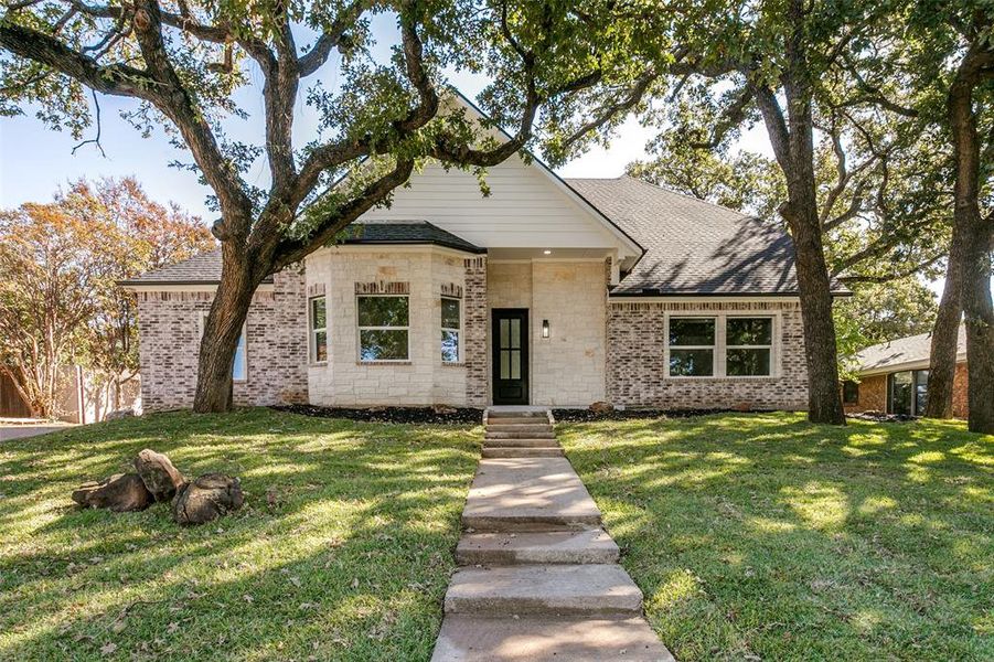 View of front of property featuring brick siding, a front lawn, and roof with shingles