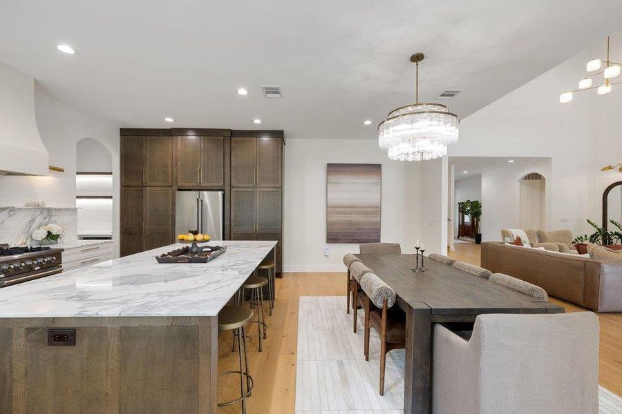 A grand kitchen and dining area with abundant counter space and rich wood flooring flows seamlessly into the living room. A grand kitchen and dining area with abundant counter space and rich wood flooring flows seamlessly into the living room.