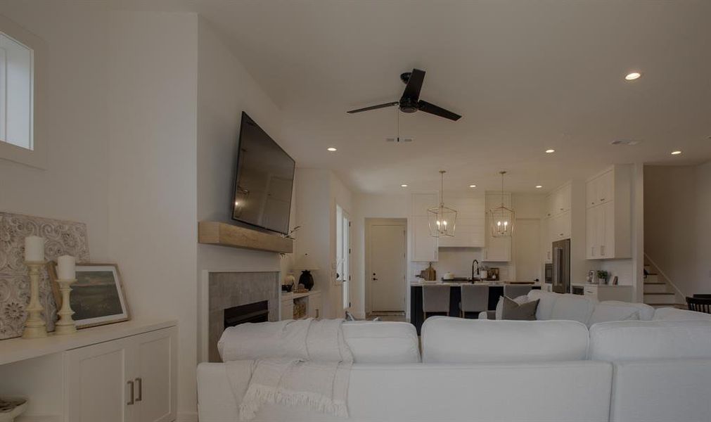 Living room featuring a tiled fireplace, ceiling fan, and sink