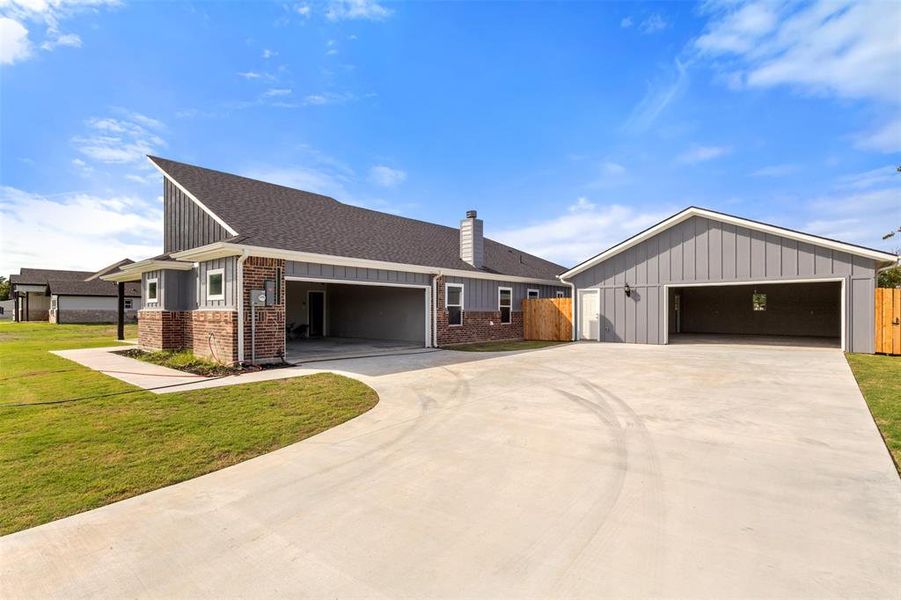 View of front facade featuring a chimney, a shingled roof, brick siding, and board and batten siding