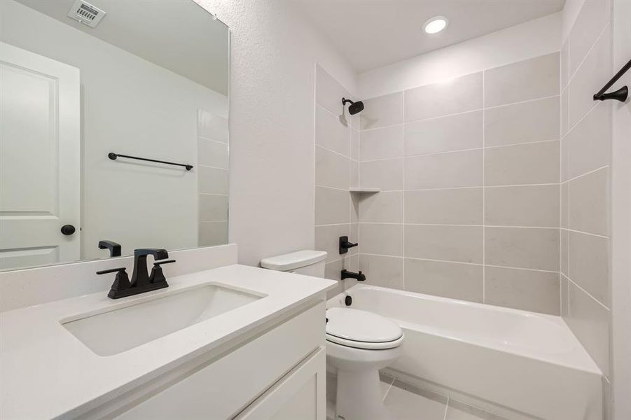 Full bathroom with tiled shower / bath, vanity, tile patterned flooring, and toilet