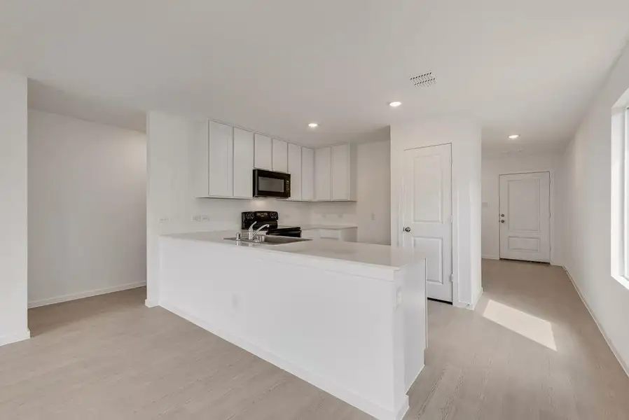 Kitchen featuring a peninsula, white cabinetry, black appliances, recessed lighting, and light wood-style flooring
