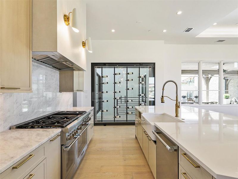 Kitchen featuring appliances with stainless steel finishes, tasteful backsplash, light wood-type flooring, ventilation hood, and sink