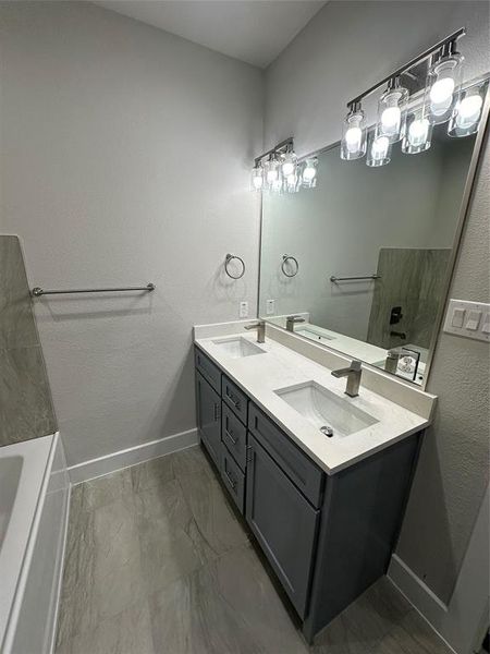 Bathroom featuring double vanity, a tub, and tile floors