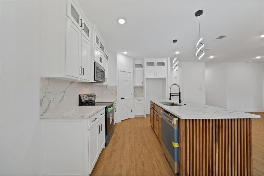 Kitchen featuring glass insert cabinets, light stone countertops, decorative backsplash, white cabinets, and recessed lighting