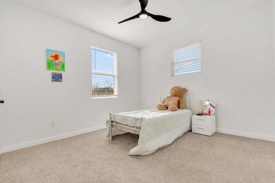 Bedroom with a ceiling fan and light colored carpet