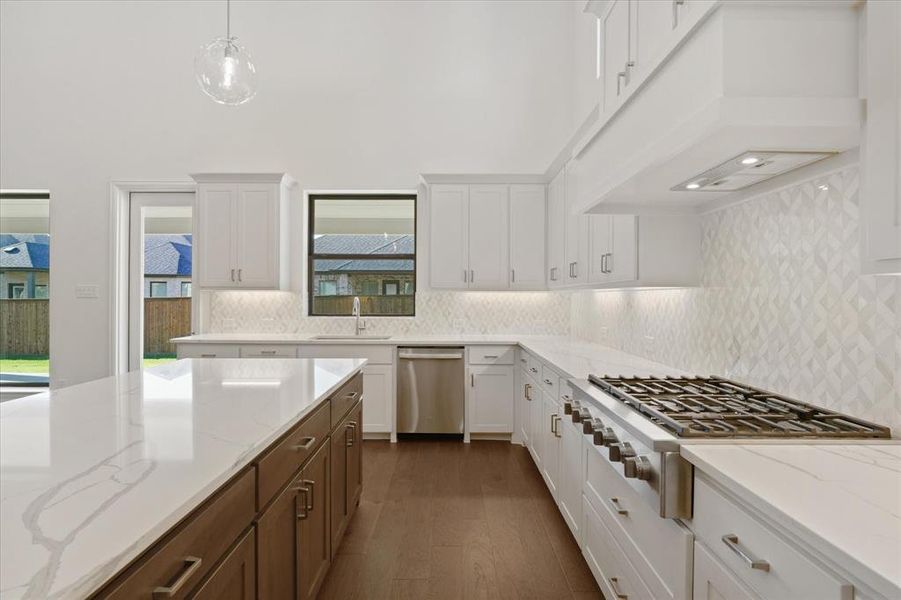 Kitchen with decorative backsplash, stainless steel appliances, and white cabinetry