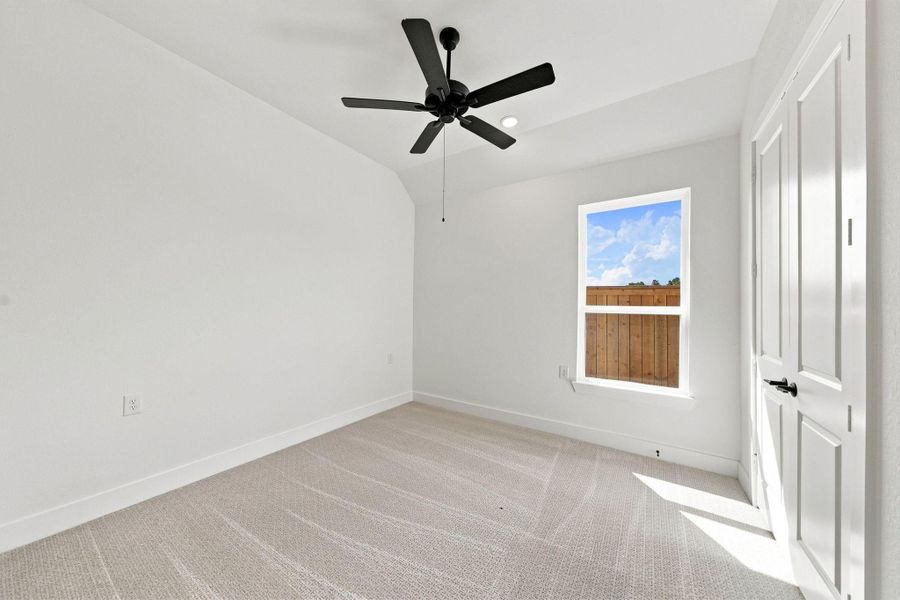 Comfortable secondary bedroom with a ceiling fan, natural light, and easy access to the home’s additional living spaces.