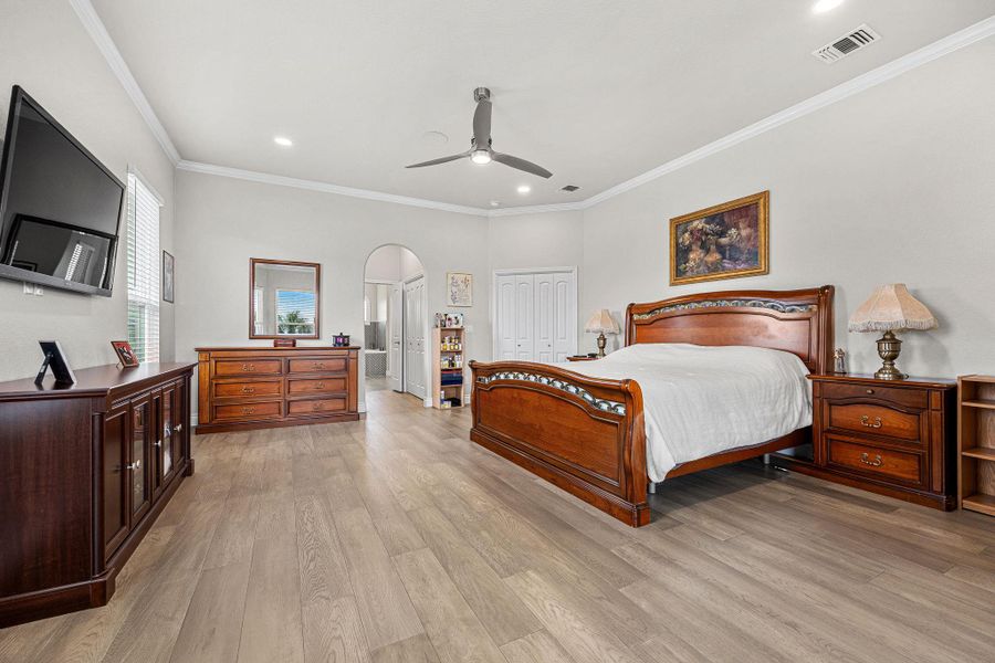 A spacious primary bedroom showcasing hardwood flooring and a stylish ceiling fan for comfort. A spacious primary bedroom showcasing hardwood flooring and a stylish ceiling fan for comfort.