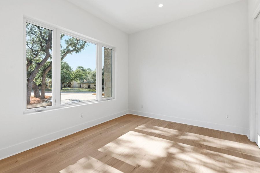 Crisp walls and rich wood flooring frame peaceful neighborhood views through expansive windows.