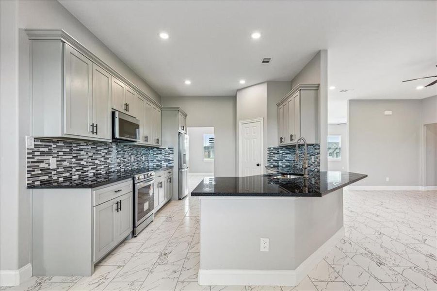 Kitchen with marble finish floor, a sink, gray cabinets, and appliances with stainless steel finishes