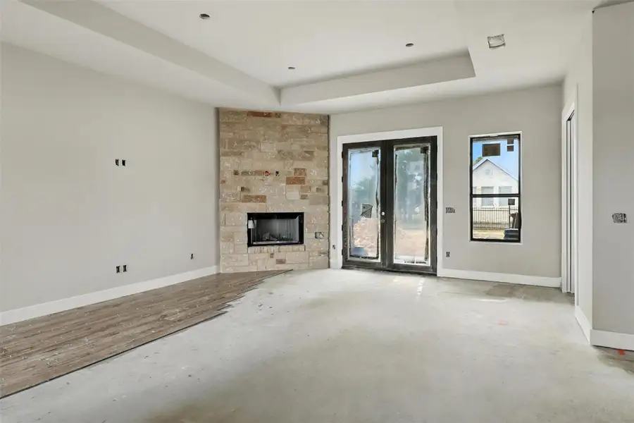 Unfurnished living room with a raised ceiling, a large fireplace, and concrete floors Unfurnished living room with a raised ceiling, a large fireplace, and concrete floors
