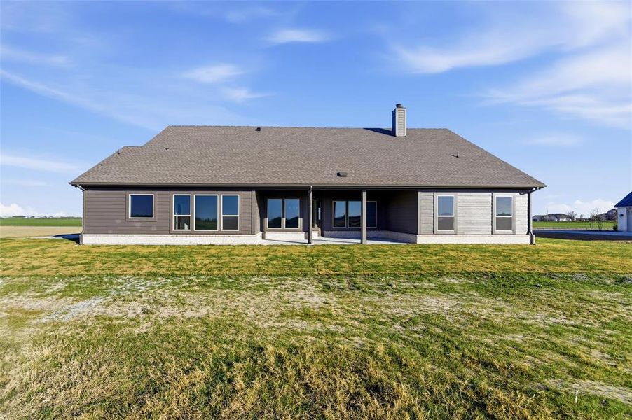 Back of property featuring a patio, a yard, a chimney, and roof with shingles