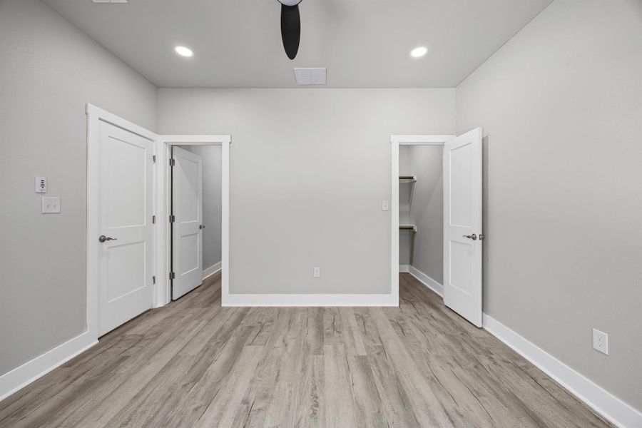 Unfurnished bedroom with light wood-style flooring, a spacious closet, a ceiling fan, and recessed lighting Unfurnished bedroom with light wood-style flooring, a spacious closet, a ceiling fan, and recessed lighting
