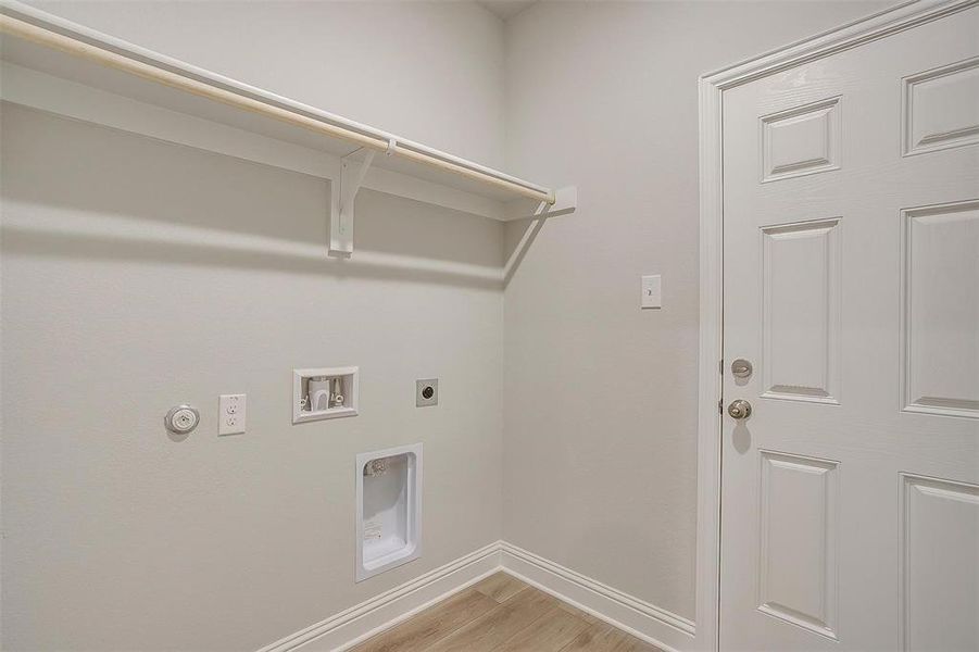 Laundry room featuring light wood finished floors, electric dryer hookup, washer hookup, and hookup for a gas dryer Laundry room featuring light wood finished floors, electric dryer hookup, washer hookup, and hookup for a gas dryer