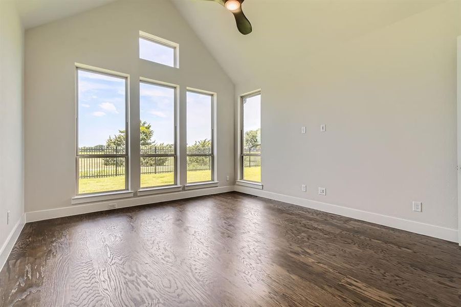 Empty room with ceiling fan, dark wood-style floors, and high vaulted ceiling Empty room with ceiling fan, dark wood-style floors, and high vaulted ceiling