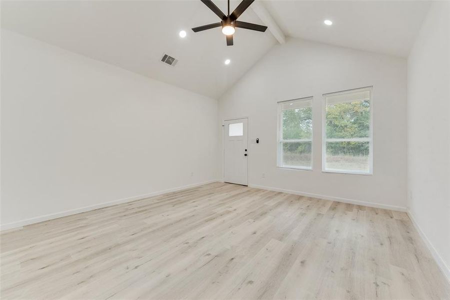 Spare room featuring high vaulted ceiling, ceiling fan, beamed ceiling, and light hardwood / wood-style flooring