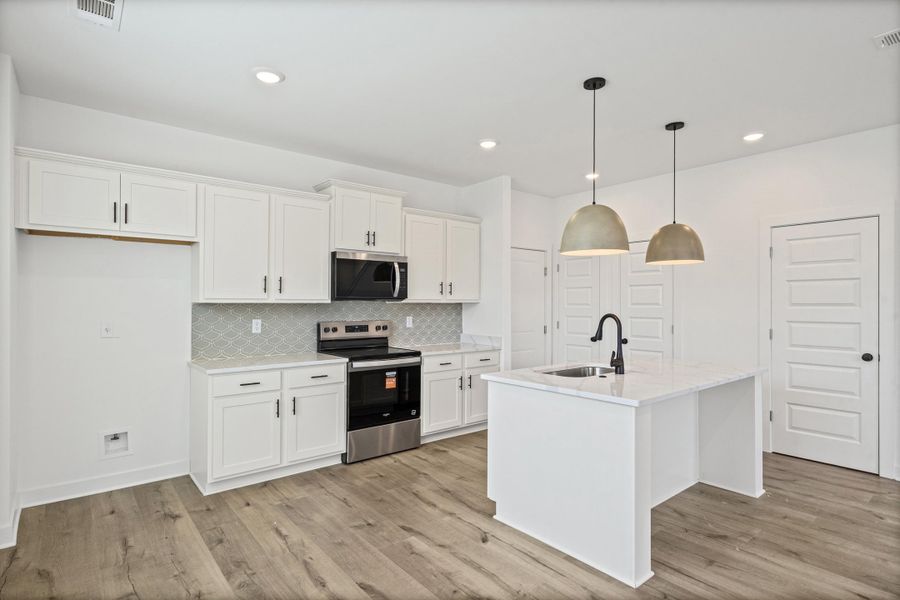 Kitchen featuring white cabinetry, stainless steel appliances, a tile backsplash, and wood-finish flooring