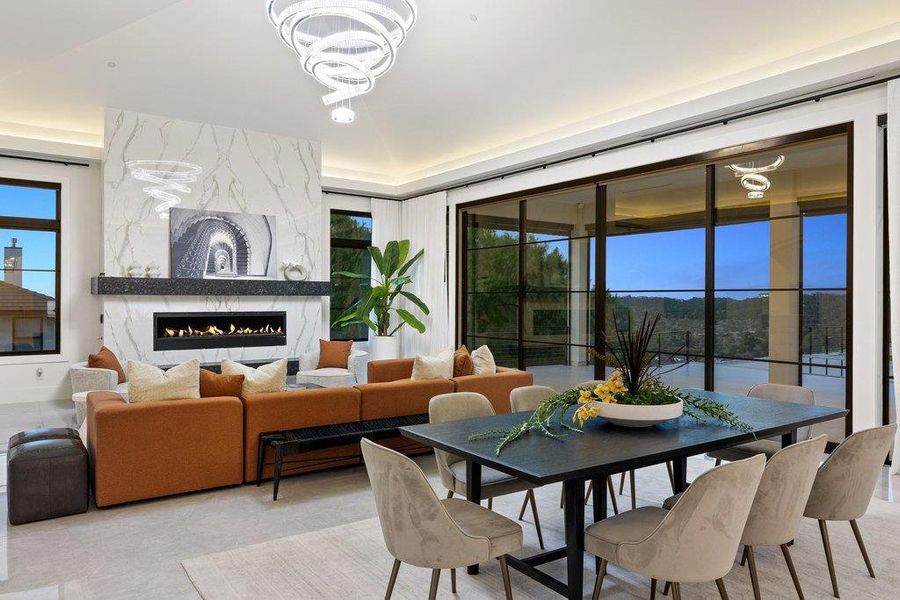 An open-concept interior showcases a sleek fireplace, recessed lighting, and expansive windows offering distant views.