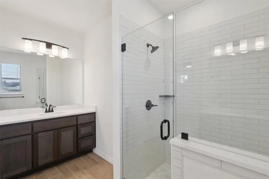 Full bathroom featuring a stall shower, vanity, and wood finished floors
