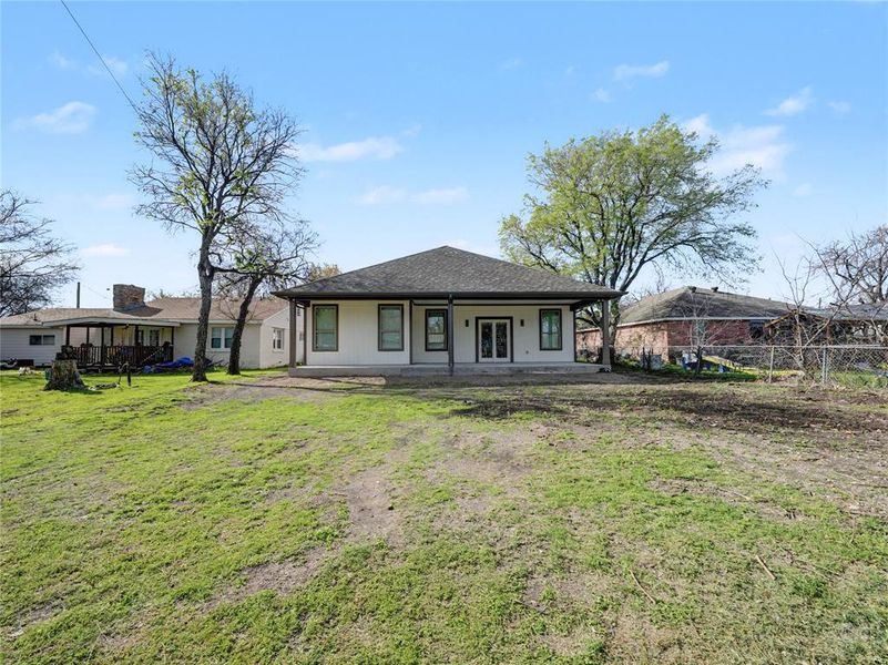 View of front of property featuring a patio, a front yard, and roof with shingles