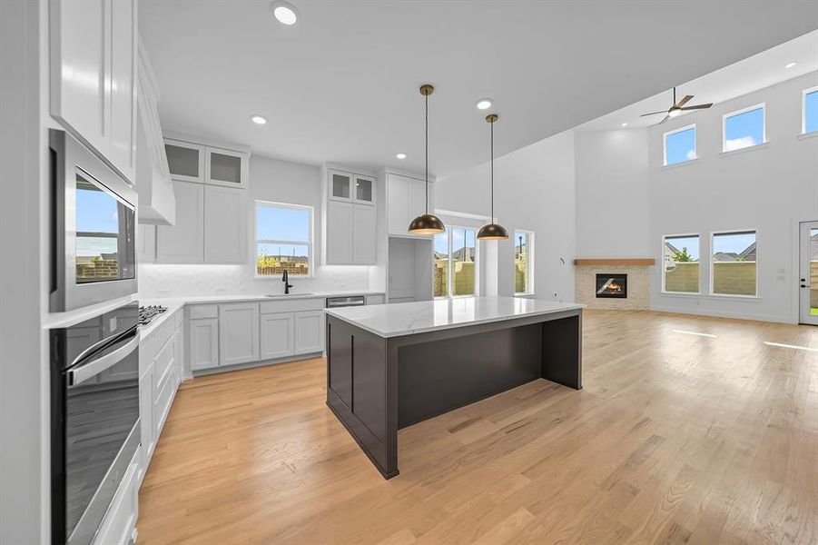 Kitchen with white cabinetry, glass insert cabinets, light wood-style flooring, light stone counters, and recessed lighting